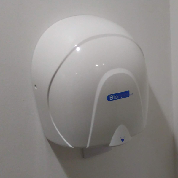 A rounded white Biodrier Hand Dryer attached to a plain white wall in a modern restroom